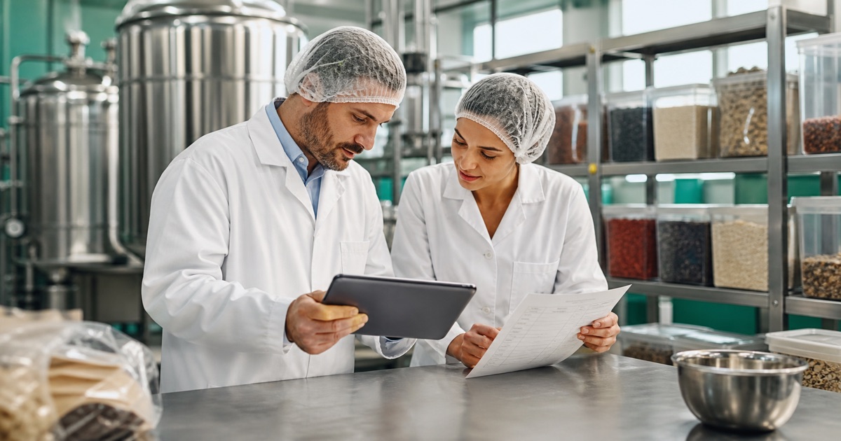 Two food production professionals reviewing a tablet and production checklist together